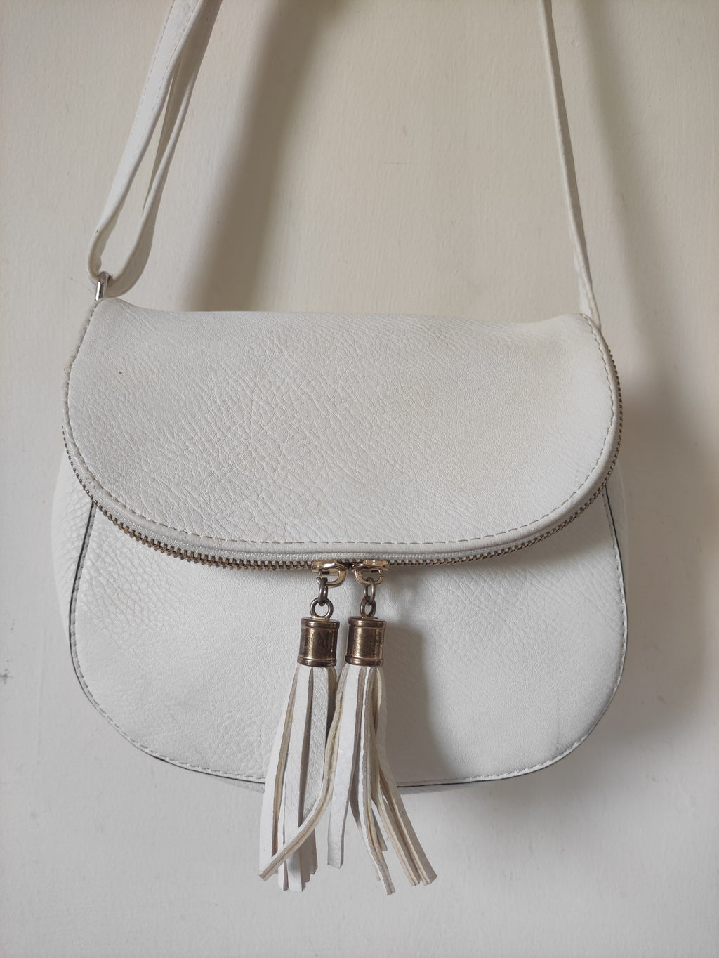 White leather handbag with tassel details on a light background