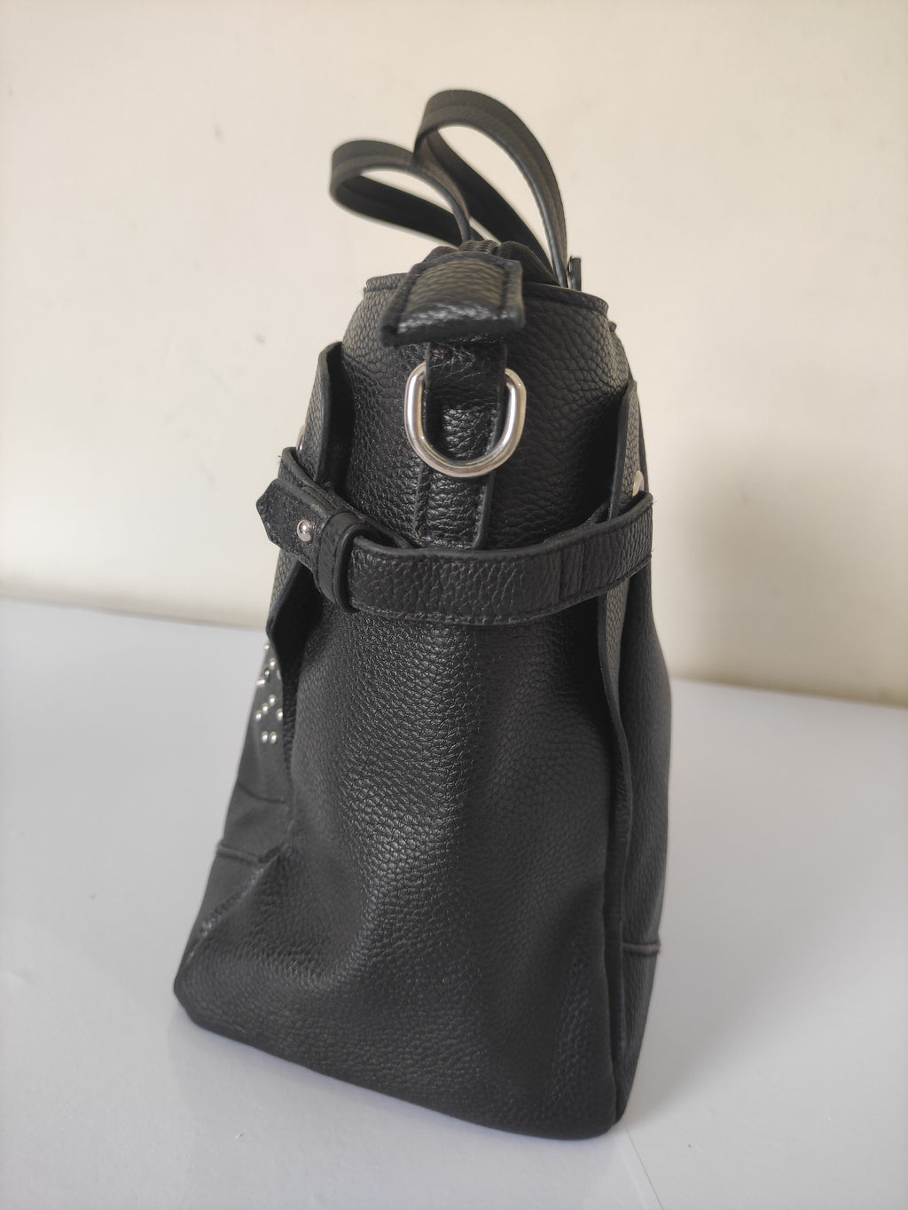 Black leather handbag with a strap on a light background