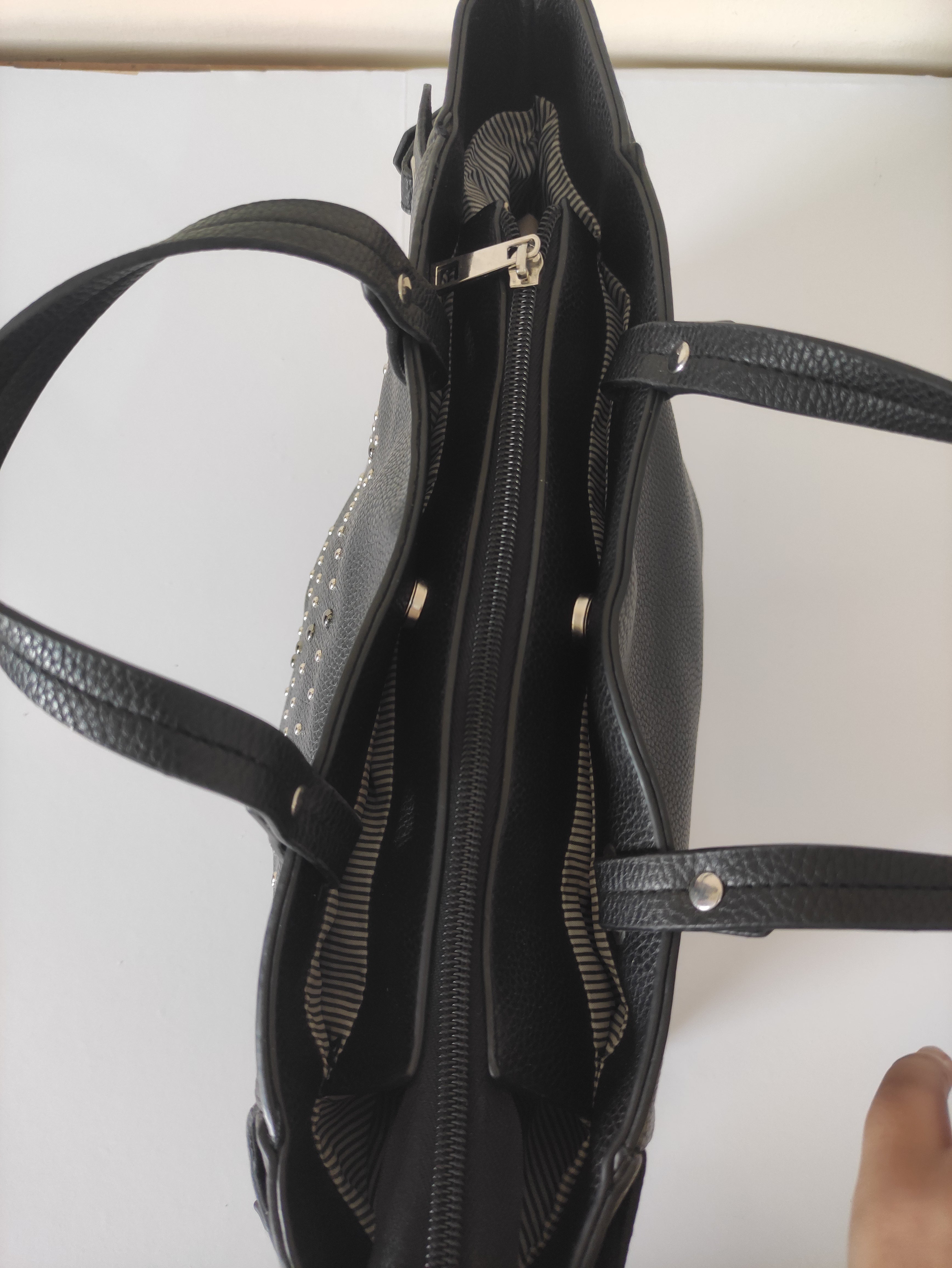 Close-up of a black handbag with visible stitching on a white background